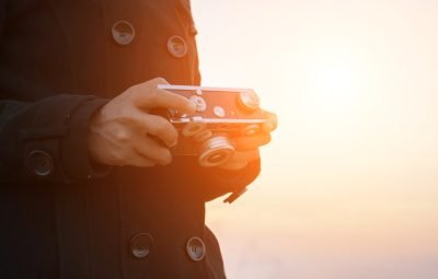 Woman hands holding retro camera with the black coat